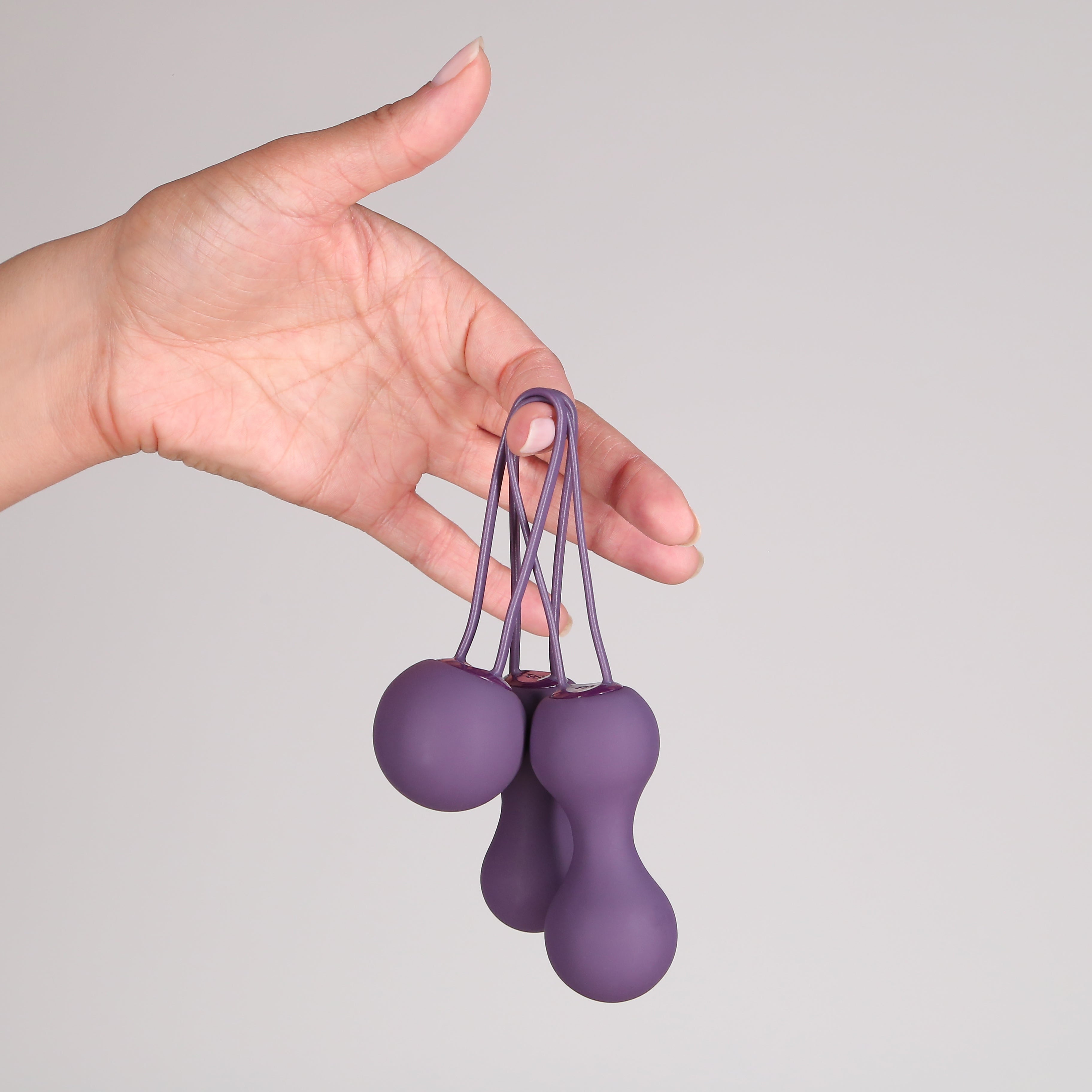 Hand holding Ami 3 Step Kegel set in Purple