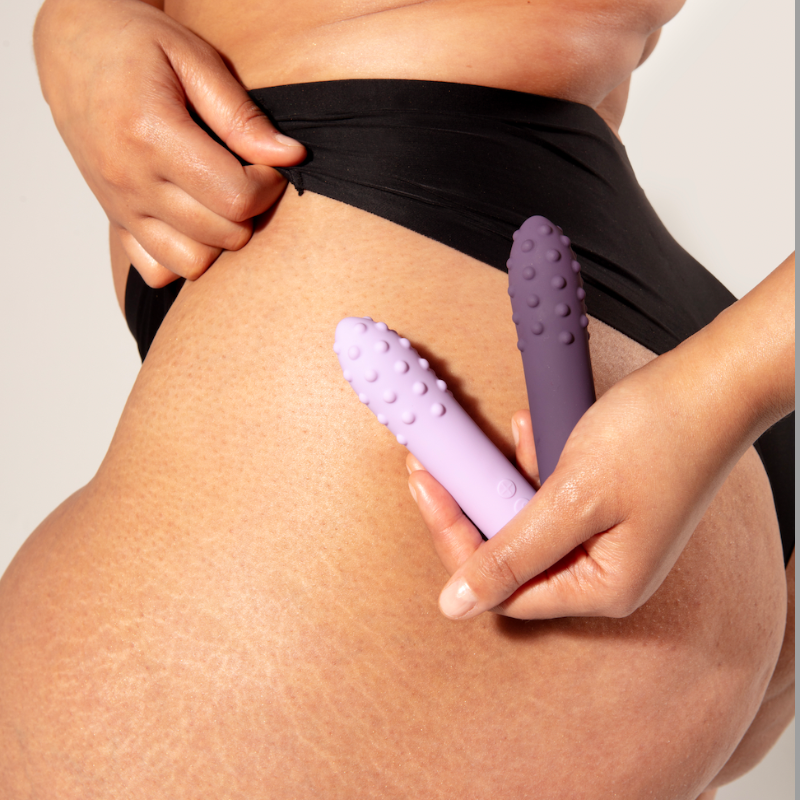 Woman holding two bullet vibrators in front of hip