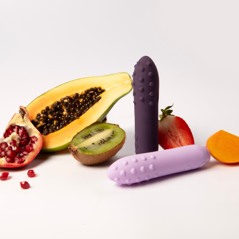 Two Je Joue Duet Vibrators in front of various fruits 