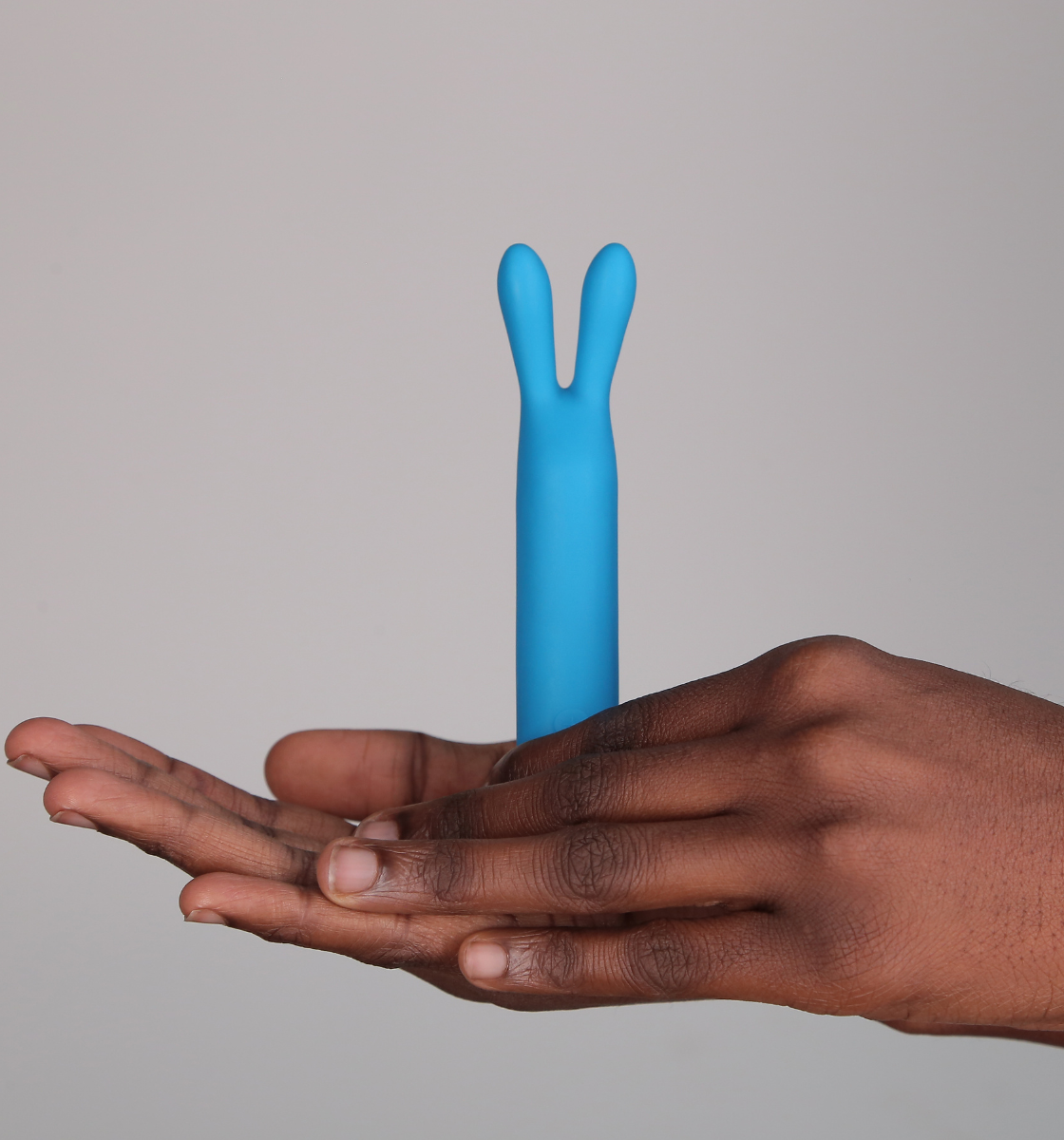 Hand holding rabbit vibrator in teal