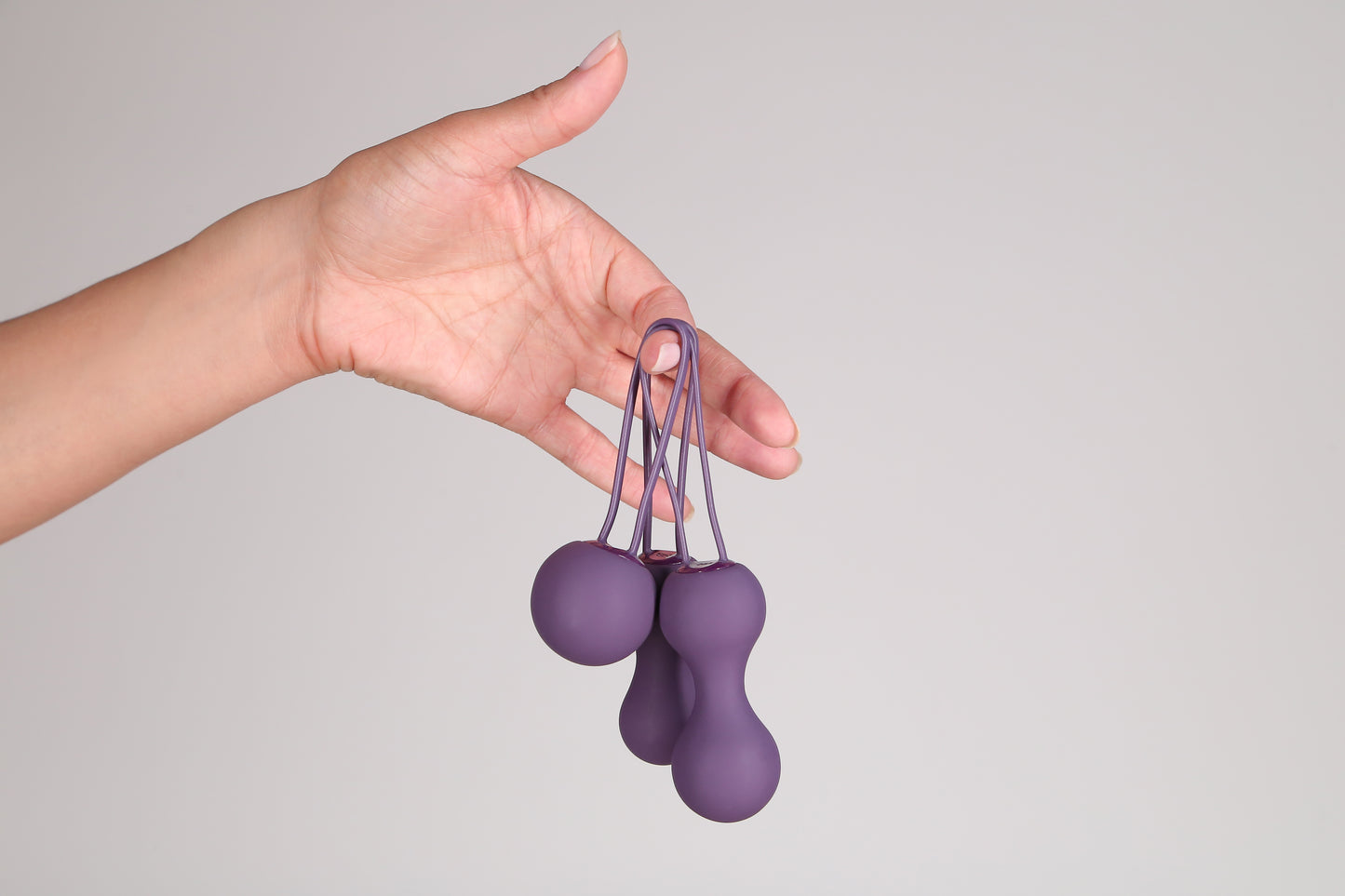 Hand holding Ami 3 Step Kegel set in Purple