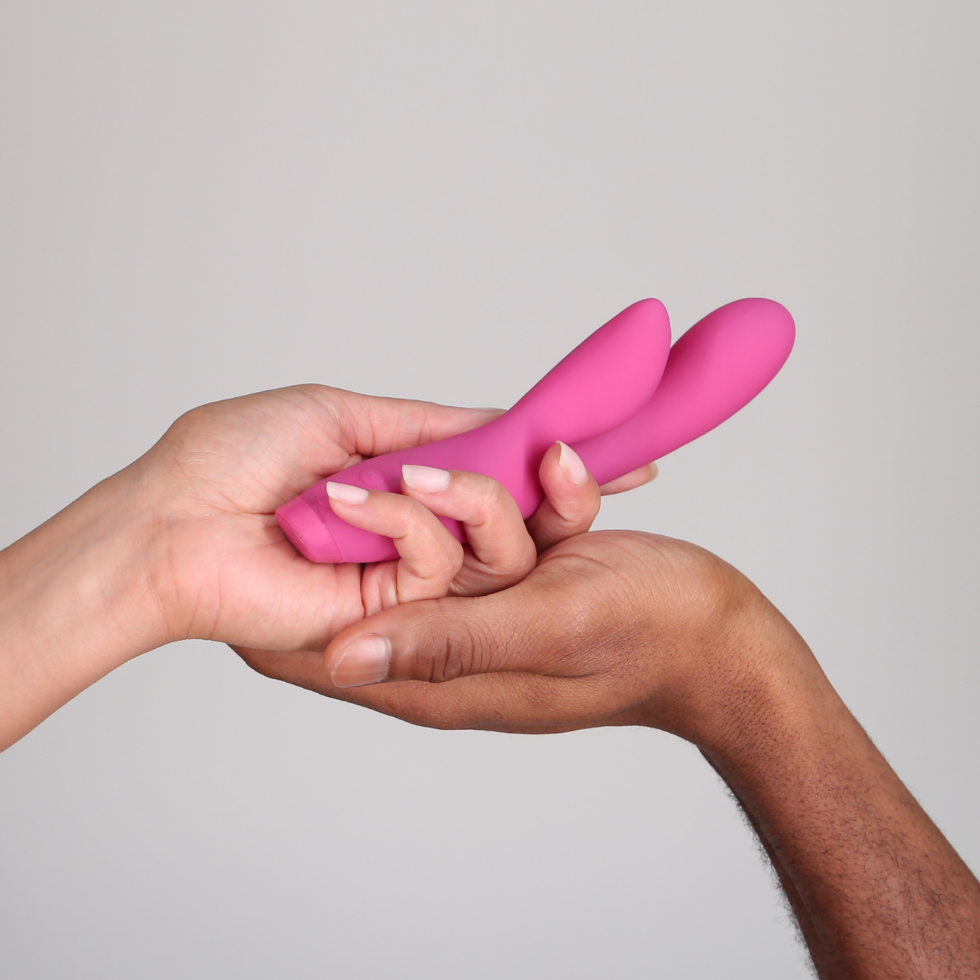 Hands holding Pink Hera vibrator on plain background 