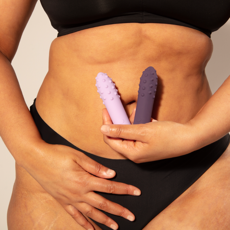 Woman holding Duet bullet vibrators in front of belly