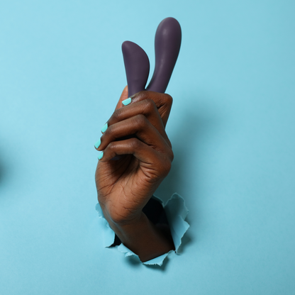 Hand holding Hera Vibrator through a blue paper wall