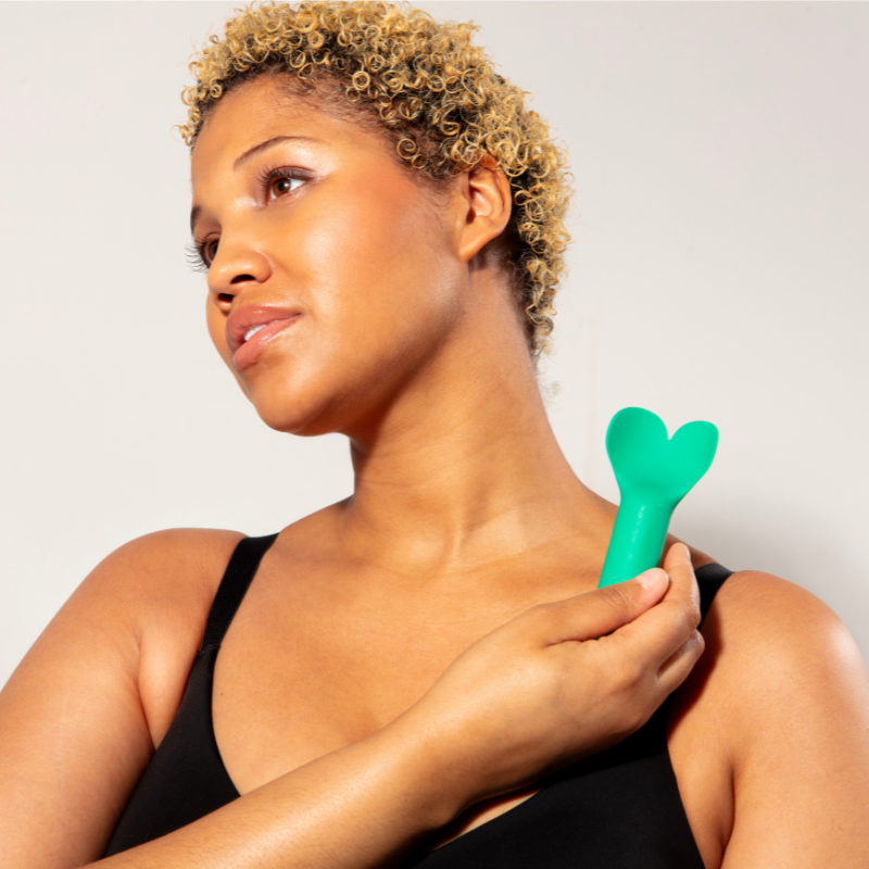 Woman holding emerald green Amour Vibrator on shoulder