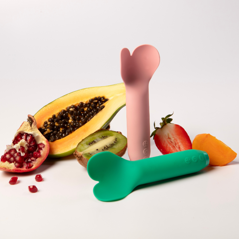 Two Je Joue Amour vibrators in front of various fruits